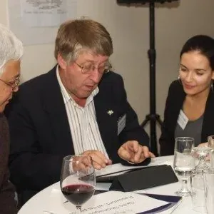 EMRC workshop delegates gathered around an iPad capturing ideas at a table