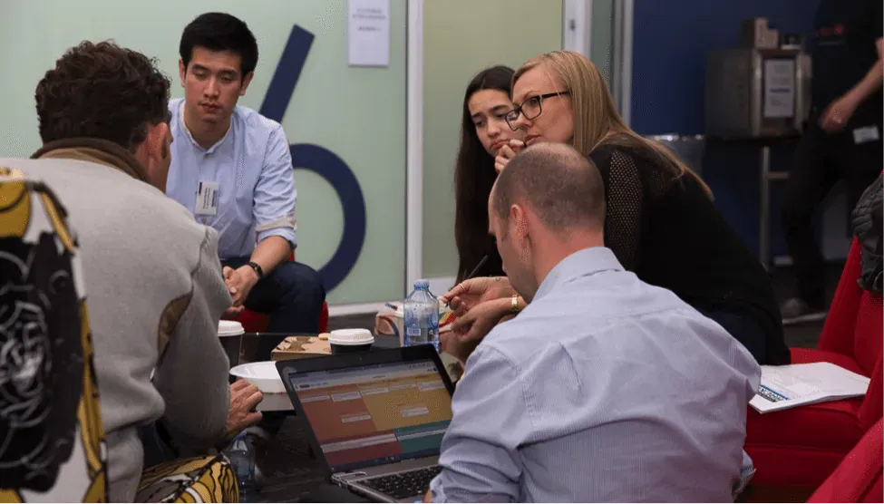 Group collaborating around a laptop at a hackathon