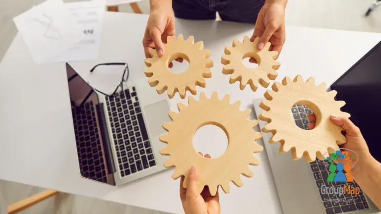 Two people fitting wooden cogwheels together at a desk symbolizing collaboration and teamwork
