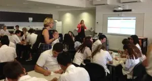 Secondary students in uniform working in groups at tables during a careers workshop
