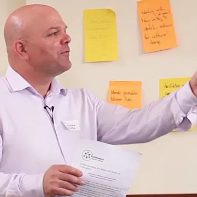 Facilitator presenting alongside sticky notes on a wall