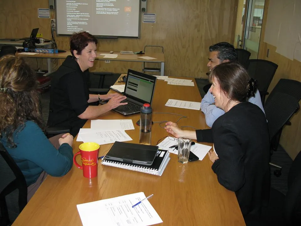 Four people collaborating around a laptop and papers at a workshop