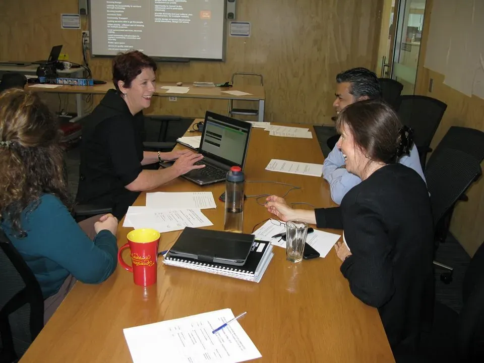 Four people collaborating around a laptop and papers at a workshop