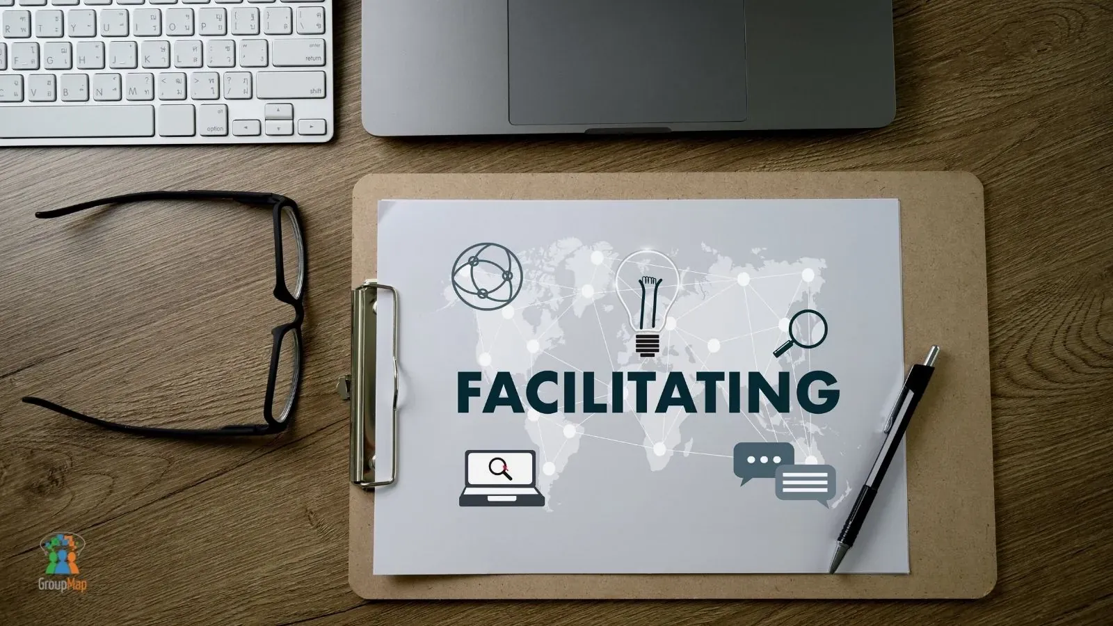 Desk with a clipboard about facilitating alongside a laptop and glasses