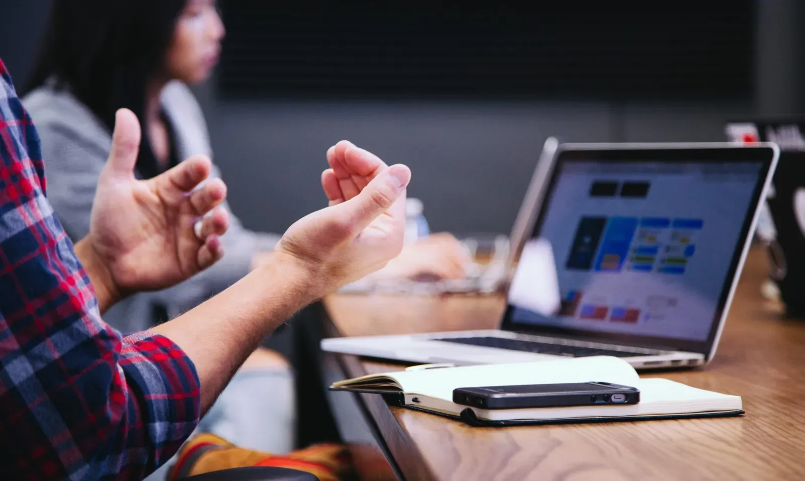 Person gesturing during a discussion beside a laptop