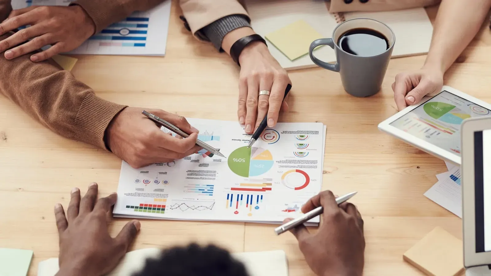 Overhead view of hands reviewing charts and graphs during a meeting