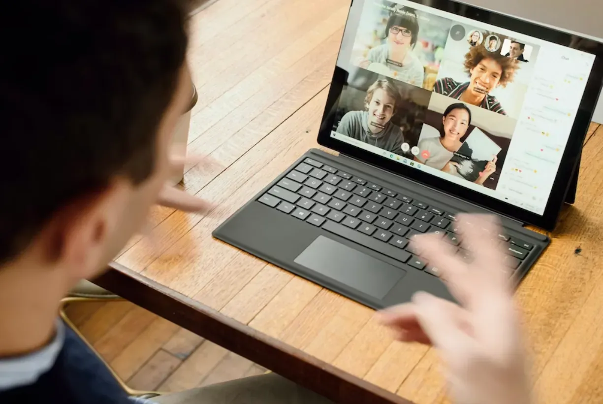 Video call participants beside a hand selecting a brainstorm option on a screen