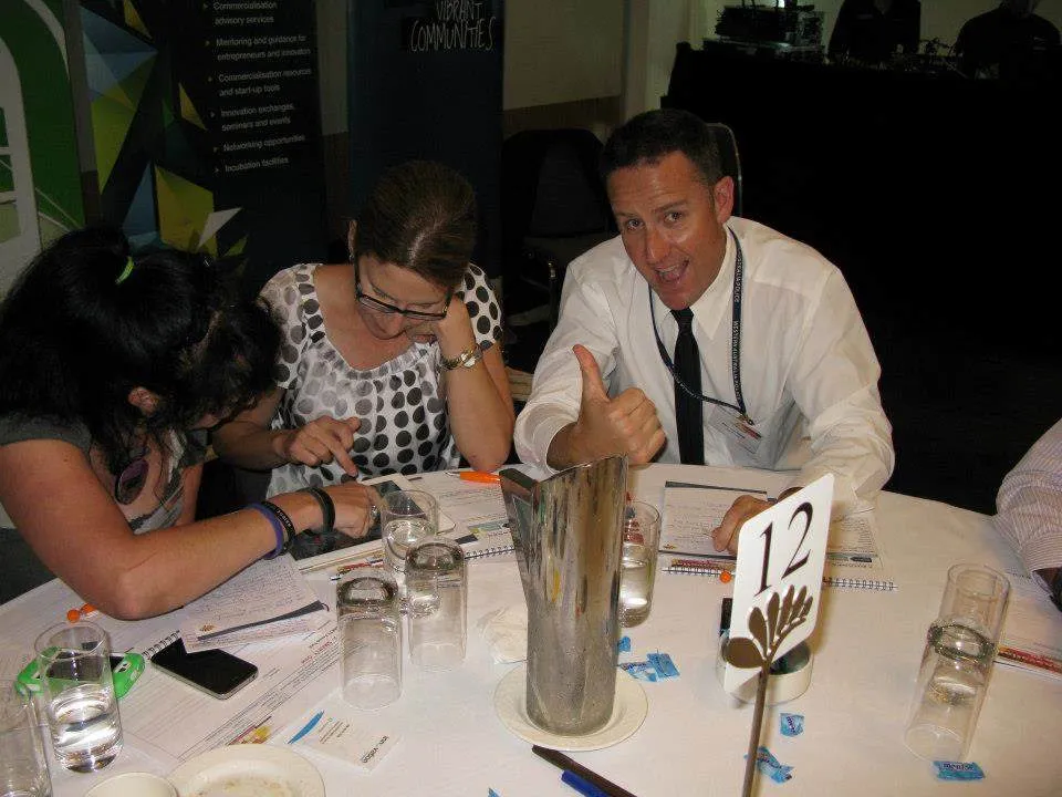 Workshop participants collaborating at a table, one giving a thumbs up