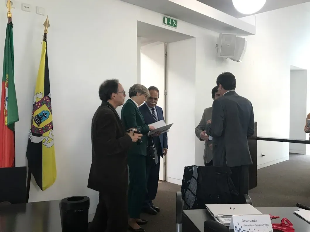 Delegates conversing beside Portuguese flags at the government health forum