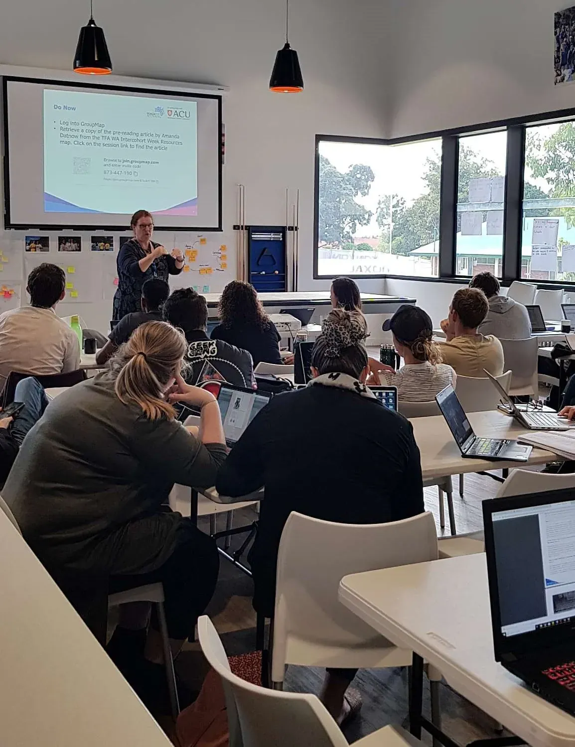 Facilitator presenting to participants using laptops in a professional development workshop