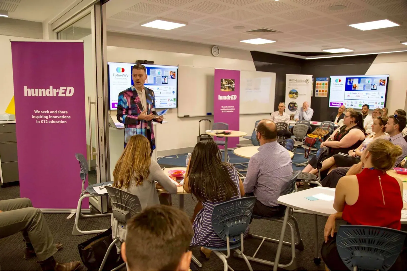 Presenter addressing a seated audience at an education innovation event