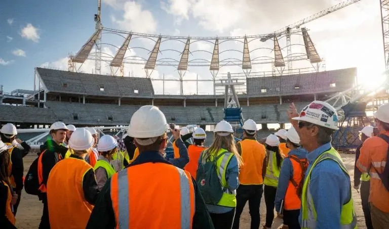 Architecture students in hi-vis vests touring a stadium construction site