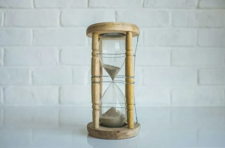 Wooden hourglass symbolizing time management for keeping meetings short and focused.