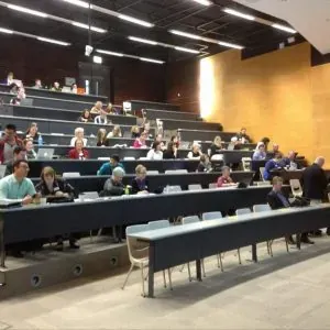 VET teachers seated with laptops in a tiered lecture theatre at the forum