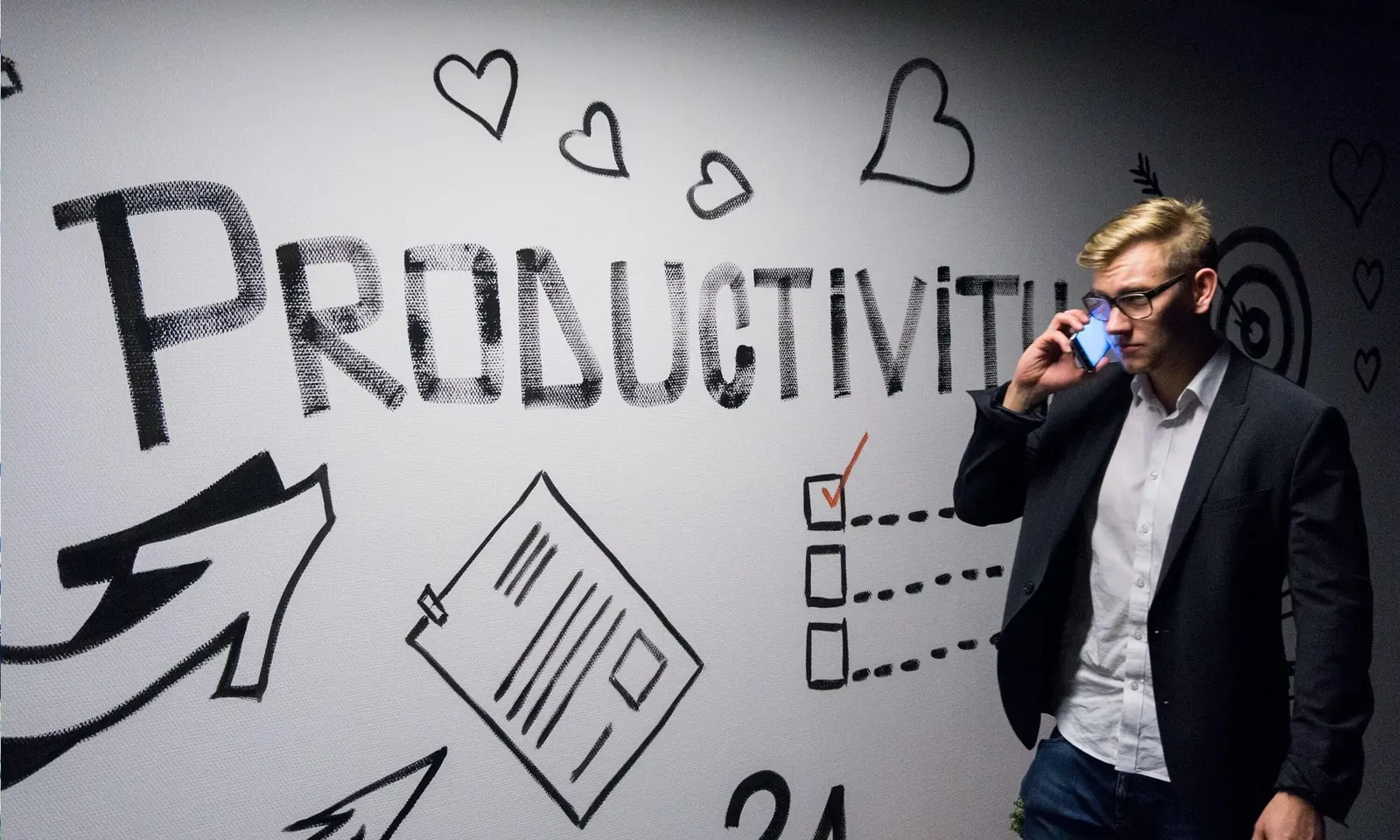 Man talking on the phone in front of a wall with productivity doodles