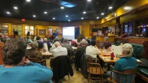 Audience seated at tables watching a presentation during a Rockville Science Cafe session
