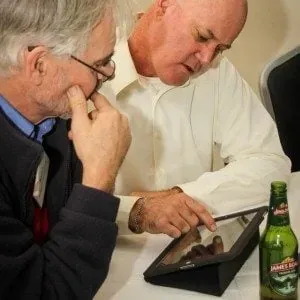 Two EMRC workshop delegates discussing ideas on a tablet at a table