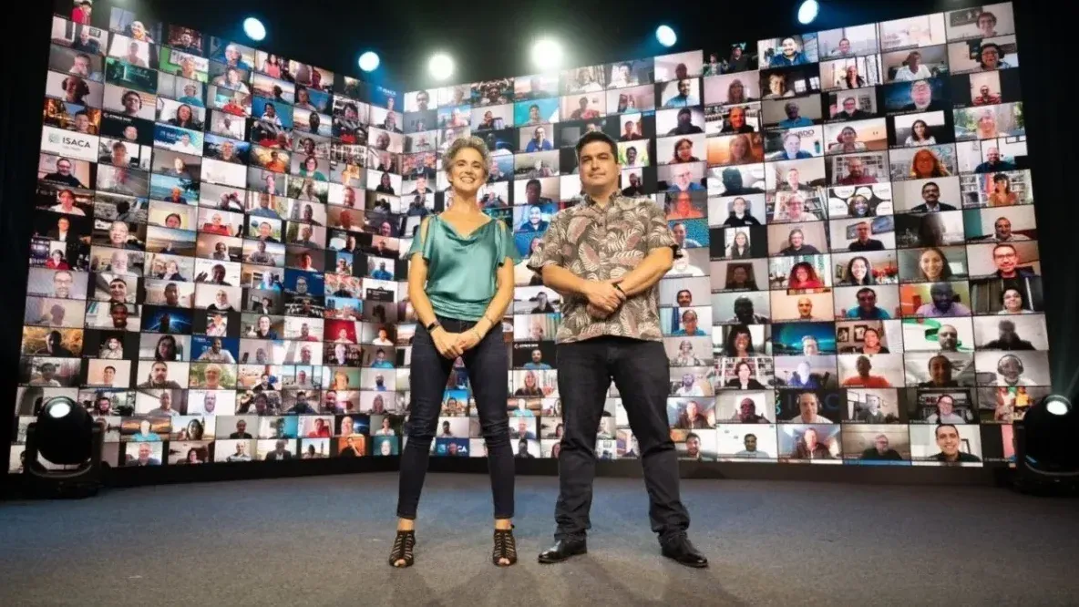 Two presenters on a stage in front of a huge curved video wall showing hundreds of remote attendees at a virtual summit