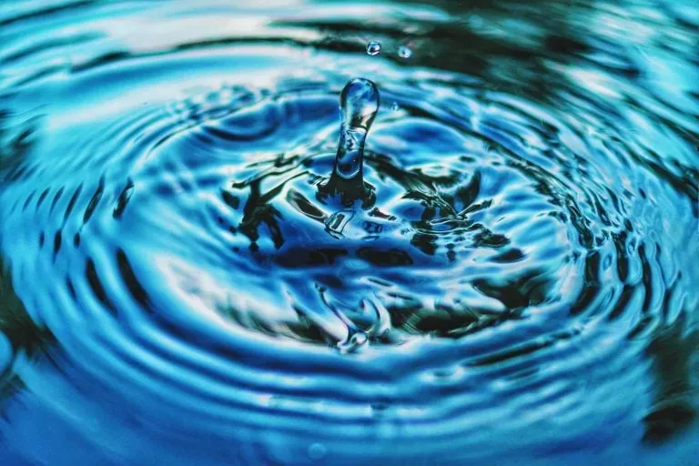 Water droplet rippling on a blue water surface